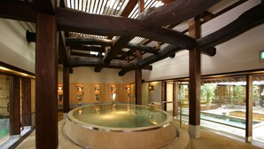 Un área de spa con hidromasaje, vigas de madera y vistas a un jardín.