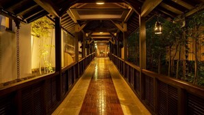 Un paseo techado con suelo de baldosas, barandillas de madera y luces colgantes.