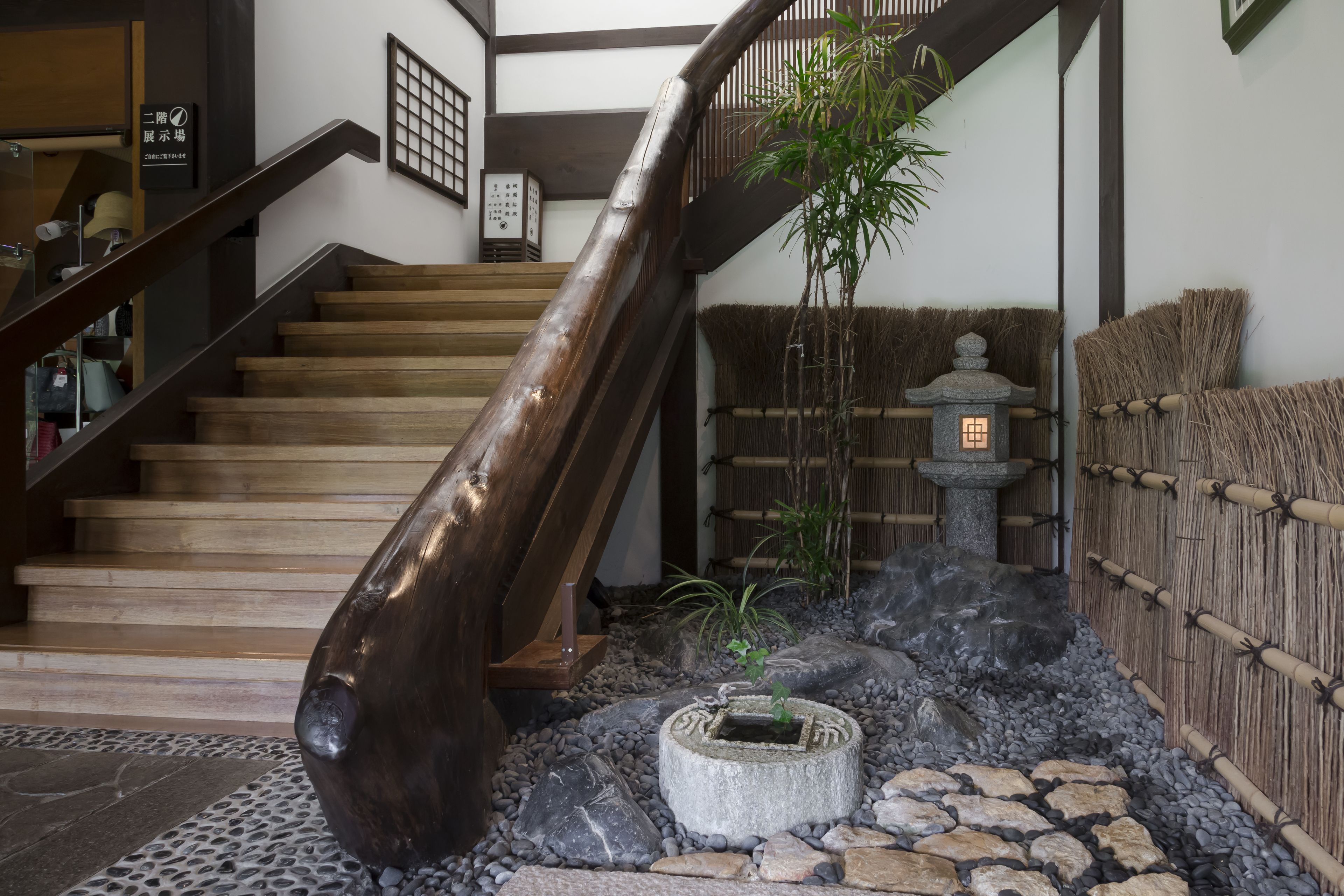 A wooden staircase leading to a second floor, a stone lantern, and a bamboo fence.