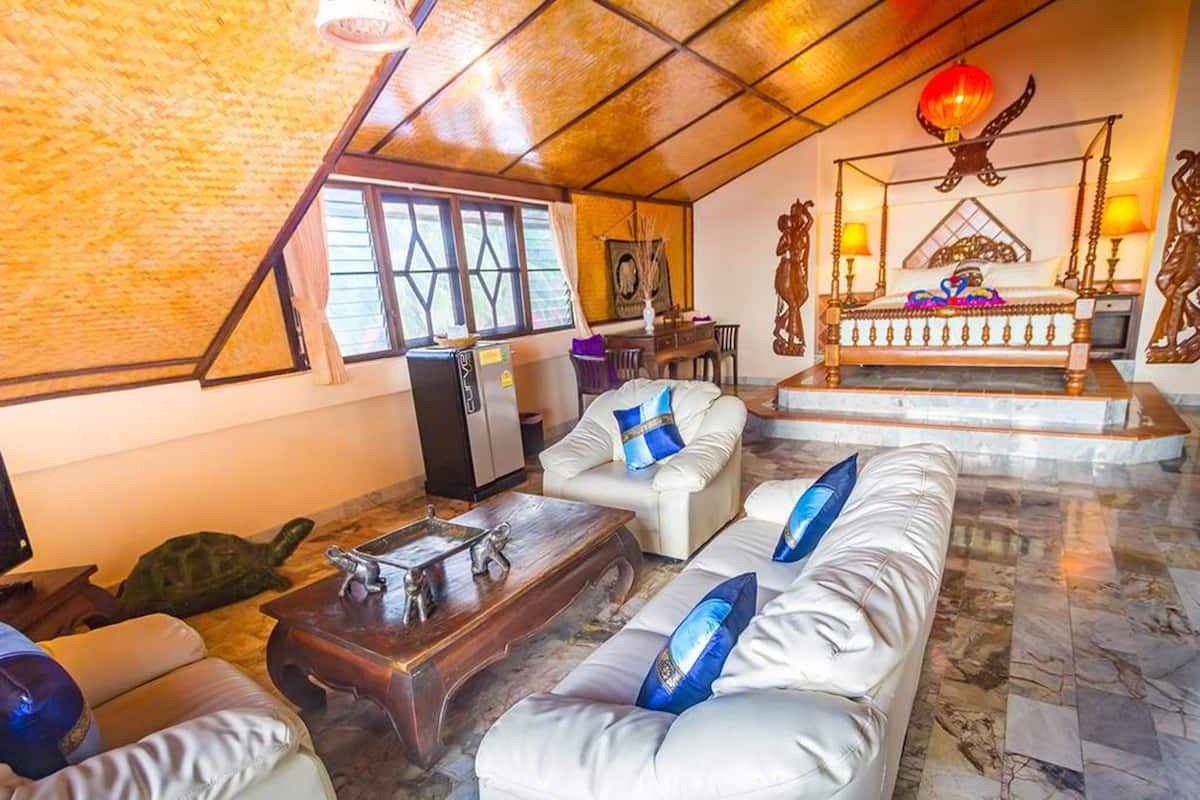 A spacious room with a high ceiling, a bed with a canopy, a sofa set, a coffee table, and a turtle on the floor.