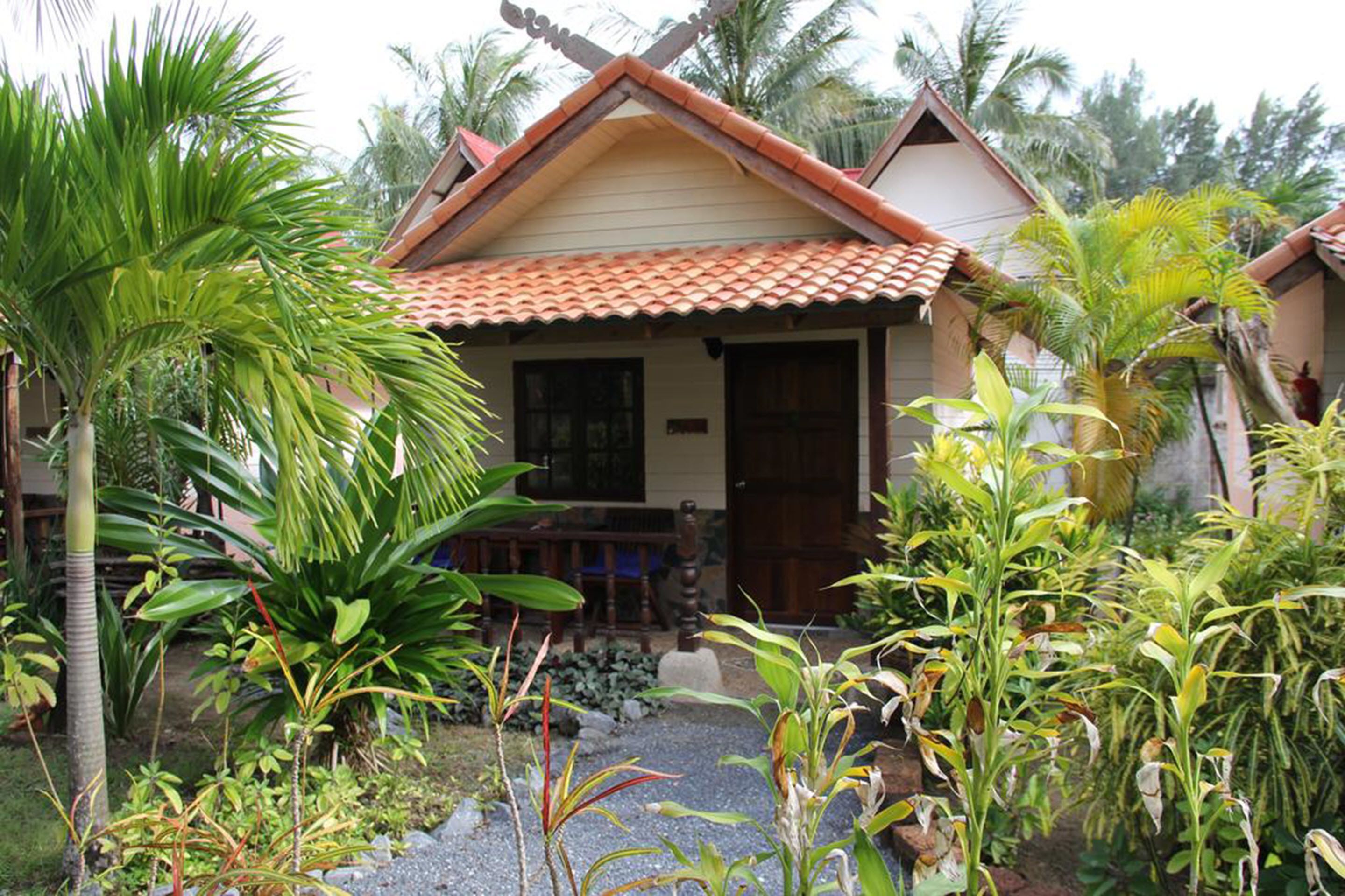 A traditional house with a tiled roof, surrounded by lush tropical plants.