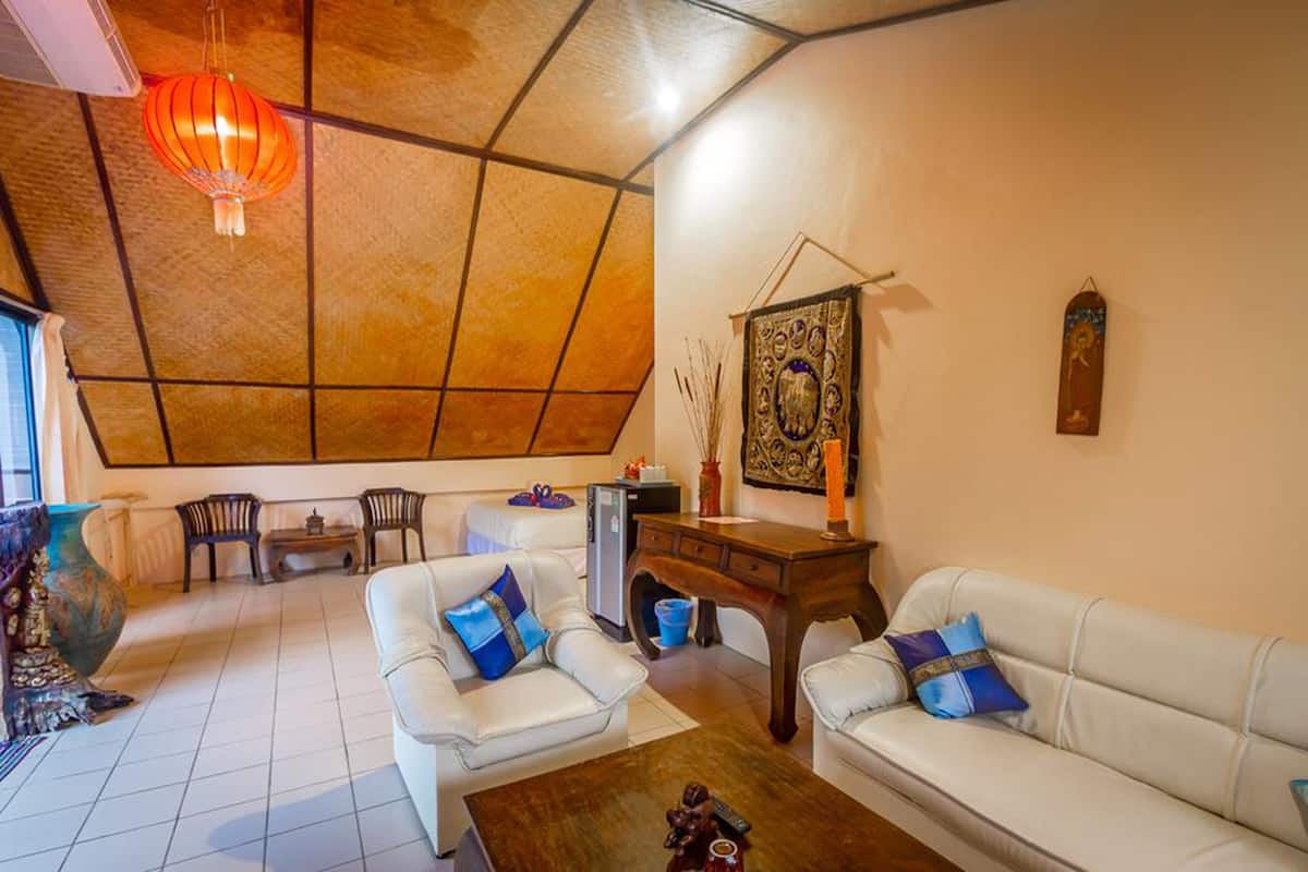 A living room with a high ceiling, white sofas with blue cushions, a wooden coffee table, and a red hanging lantern.