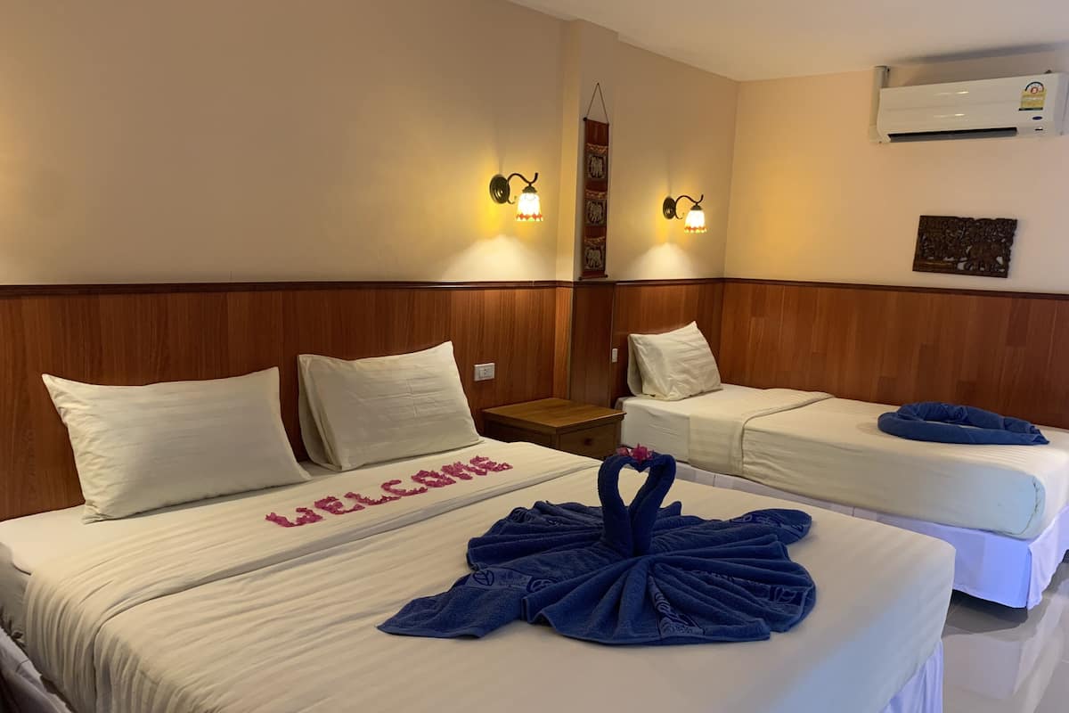 A hotel room with two beds, each with white linens and pillows. There is a decorative towel arrangement on the bed in the foreground.