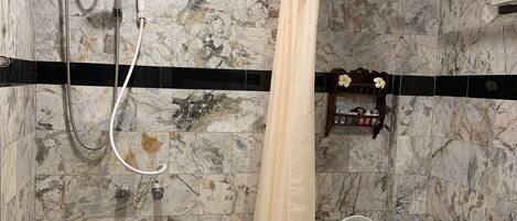 A bathroom with a shower, toilet, and marble walls.