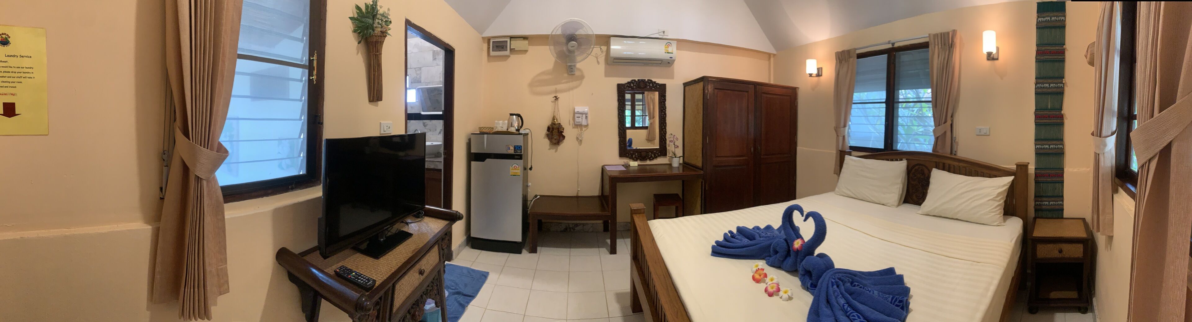 A hotel room with a bed, a desk, a television, a wardrobe, and a bathroom.