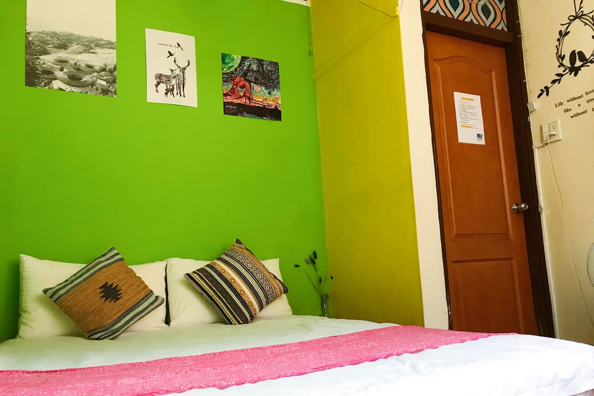 A room with a bed, green walls, and a door with a sign.