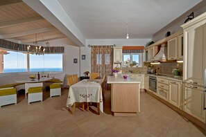 Une cuisine spacieuse avec un coin repas, de grandes fenêtres et une vue sur la mer.