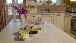 A kitchen with a marble countertop, various food items, a vase with flowers, and a view of the outdoors. - Sellia Resort (Agios Vasileios)