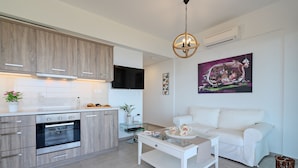 A modern kitchen with wooden cabinets, a built-in oven, and a glass coffee table. - Sellia Resort (Agios Vasileios)