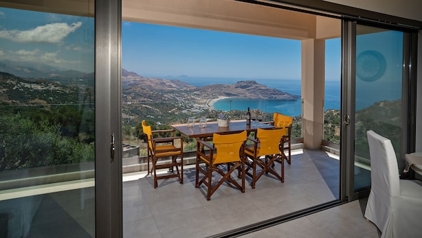 A balcony with a table and chairs, overlooking a scenic coastal landscape. - Sellia Resort (Agios Vasileios)