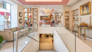 A modern hotel lobby with a staircase, glass railings, and a variety of furniture and decor. - Sé Boutique Hotel (Funchal)