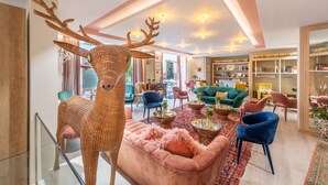 A spacious living room with a large woven deer sculpture, plush seating, and a variety of colorful chairs. - Sé Boutique Hotel (Funchal)