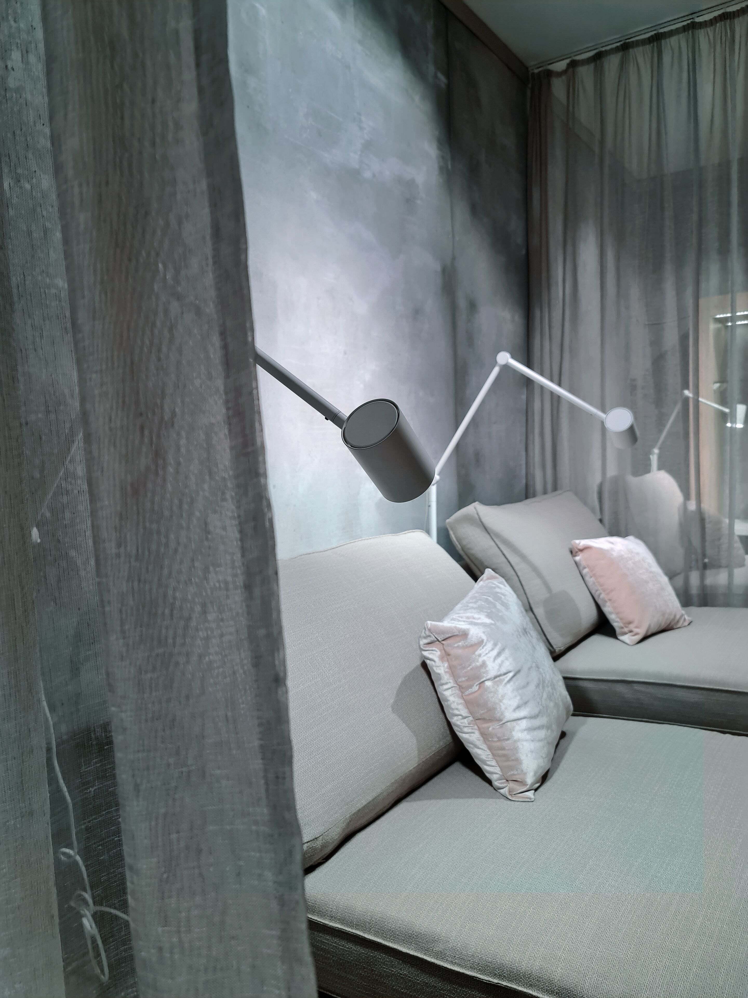 A modern living room with a sofa, two lamps, and a large window with curtains.