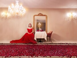 A room with a large mirror, a table with a white tablecloth, and a red carpet.
