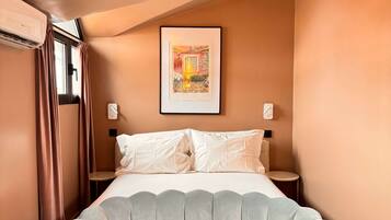 Ein Schlafzimmer mit einem Bett, einem gerahmten Bild an der Wand und einem kleinen Tisch mit einer Kerze.