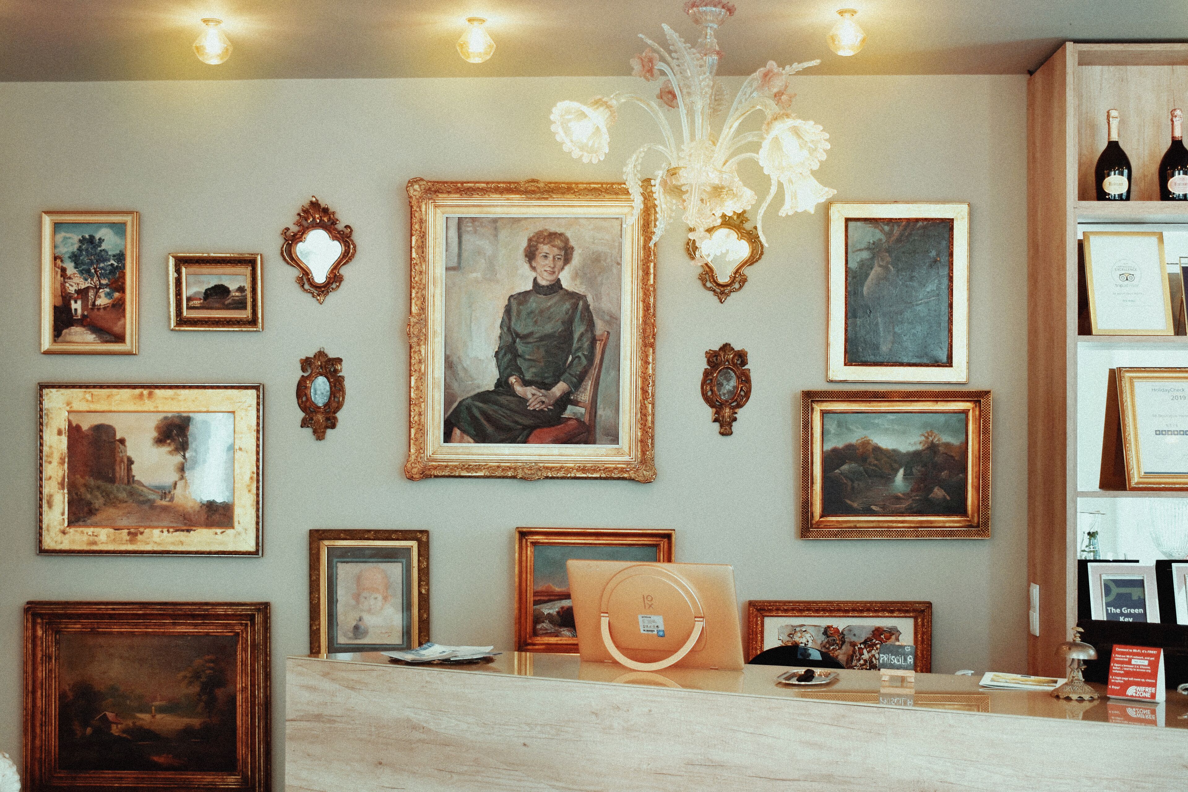 A room with a reception desk, framed artwork on the walls, and a chandelier.