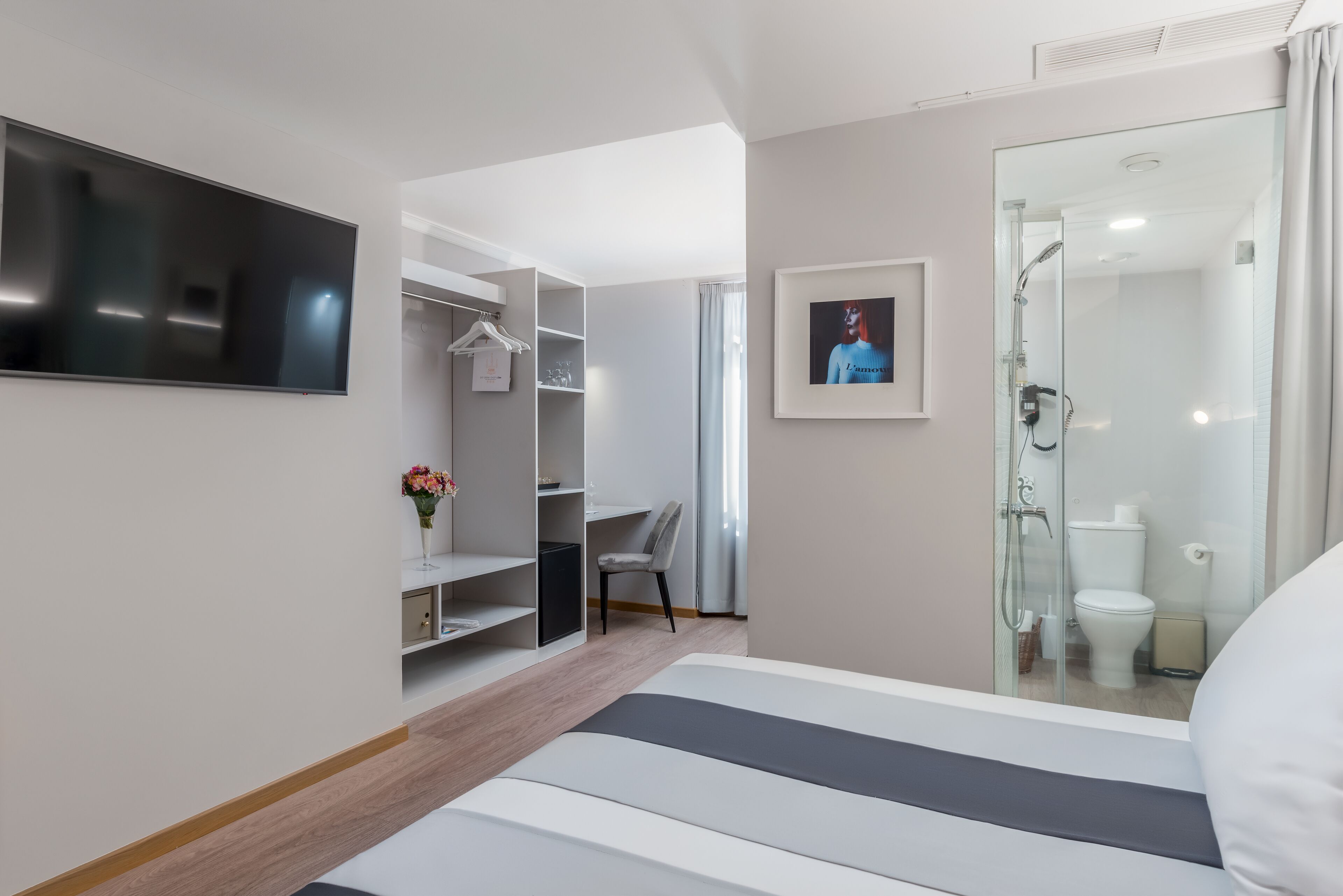 Une chambre d’hôtel moderne équipée d’un lit, d’une télévision, d’une douche et d’un espace bureau.
