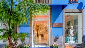 A boutique hotel entrance with a blue facade, a glass door, and a sign reading "SBH boutique hotel". - Sé Boutique Hotel (Funchal)
