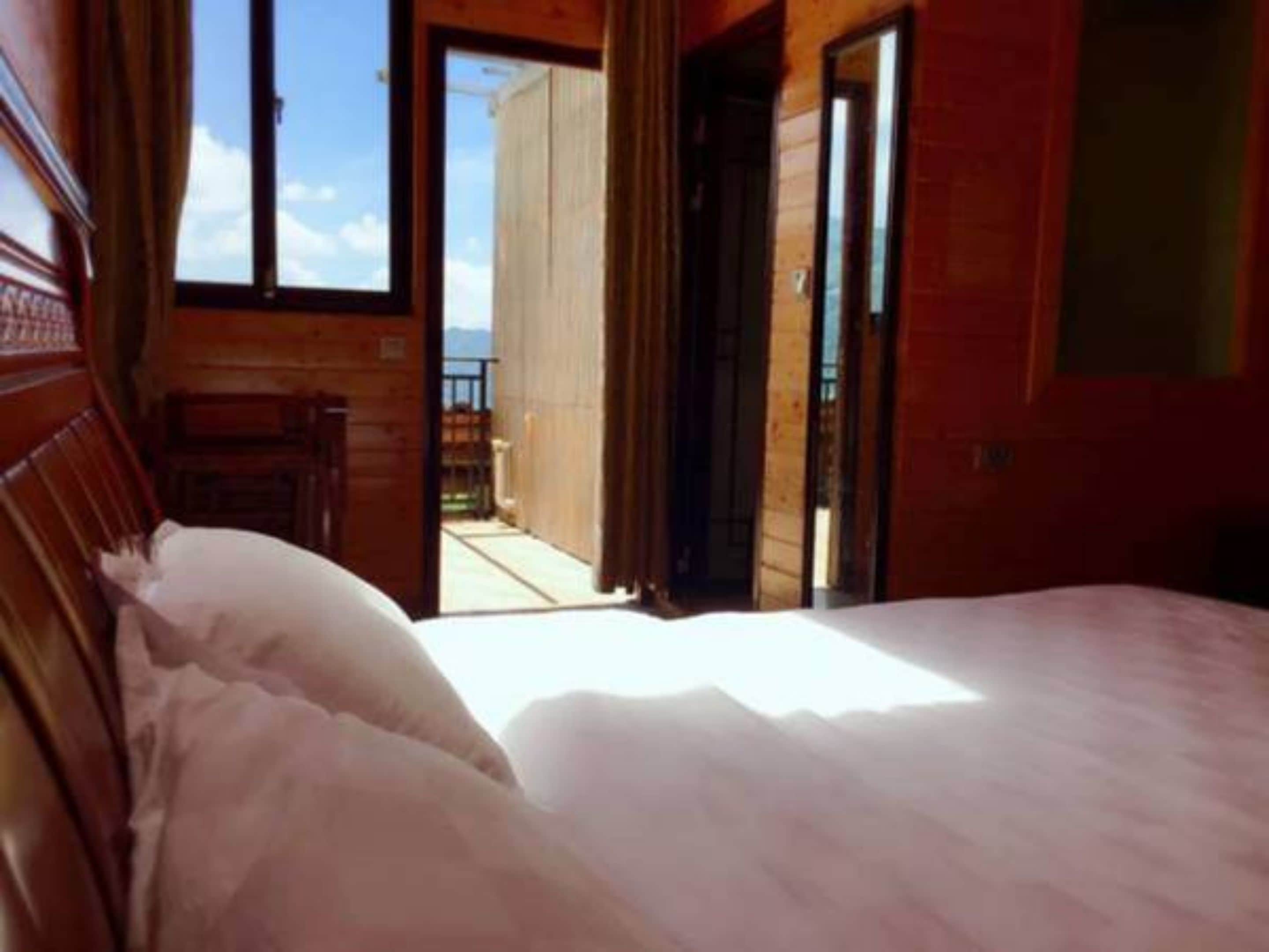 A bedroom with a bed, wooden walls, and a view of the outdoors.
