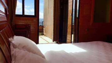 A bedroom with a bed, wooden walls, and a view of the outdoors.