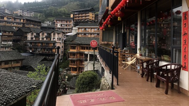 Um edifício tradicional com varanda, lanternas vermelhas e uma placa indicando uma agência de viagens.