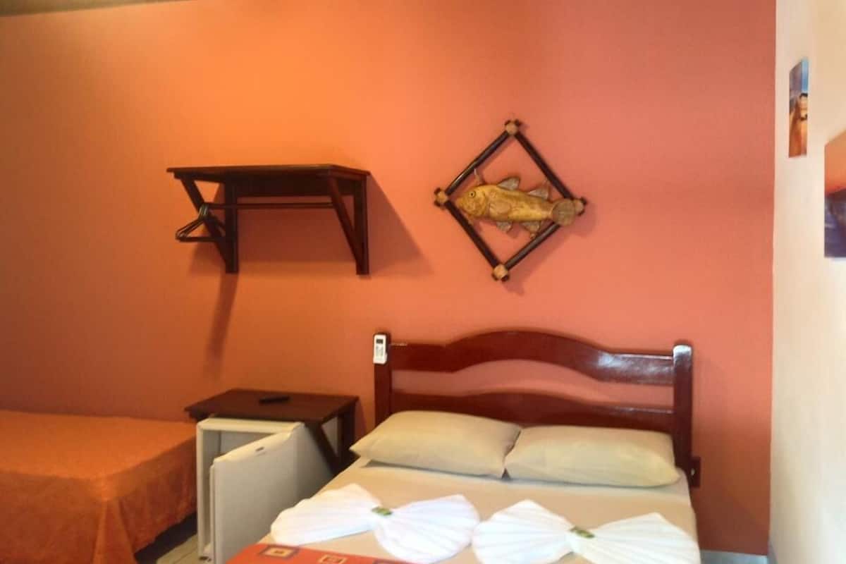 A room with a bed, a small table, a shelf, and a fish decoration on the wall.