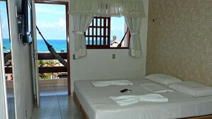 A bedroom with a bed, a TV, and a view of the ocean. - Pousada Praiana (Tibau do Sul)