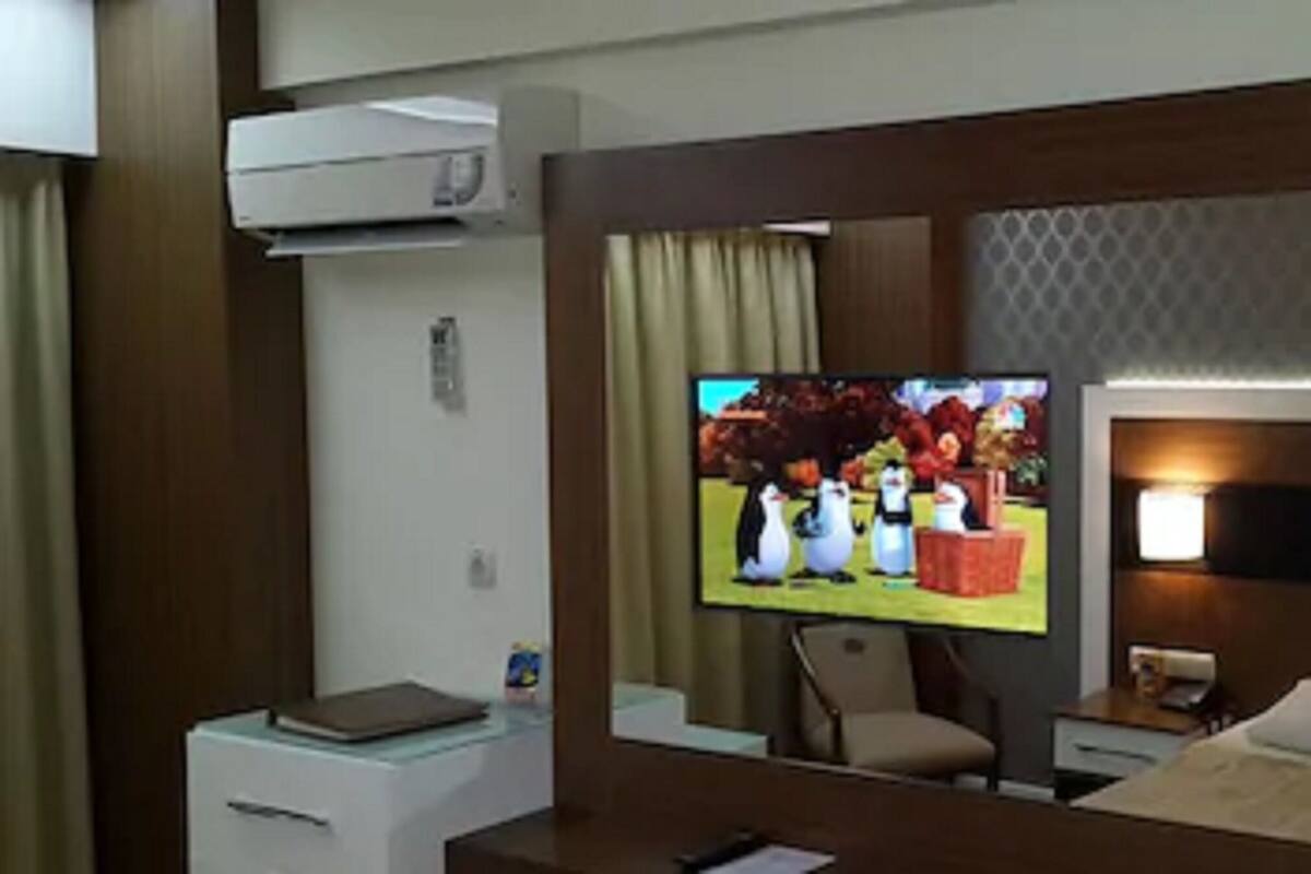 A hotel room with a television, a desk, a chair, and a bed.