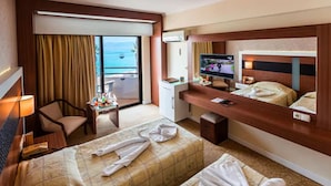 A hotel room with a balcony, a desk with a computer, a bed, and a TV. - Derici Hotel (Kusadasi)