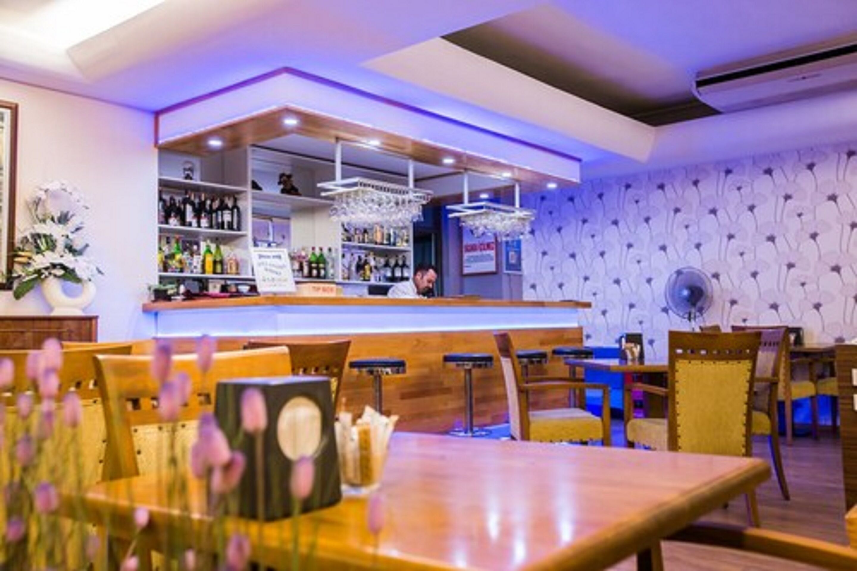 Ein Restaurant mit Bar, Holztischen und -stühlen.