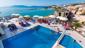 A rooftop pool area with multiple swimming pools, sun loungers, and umbrellas. - Derici Hotel (Kusadasi)