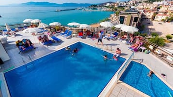 Alberca techada, alberca al aire libre y sombrillas en la alberca