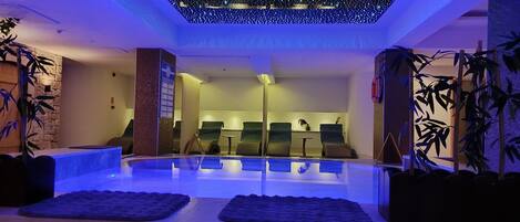 A spa area with a pool, seating, and plants.