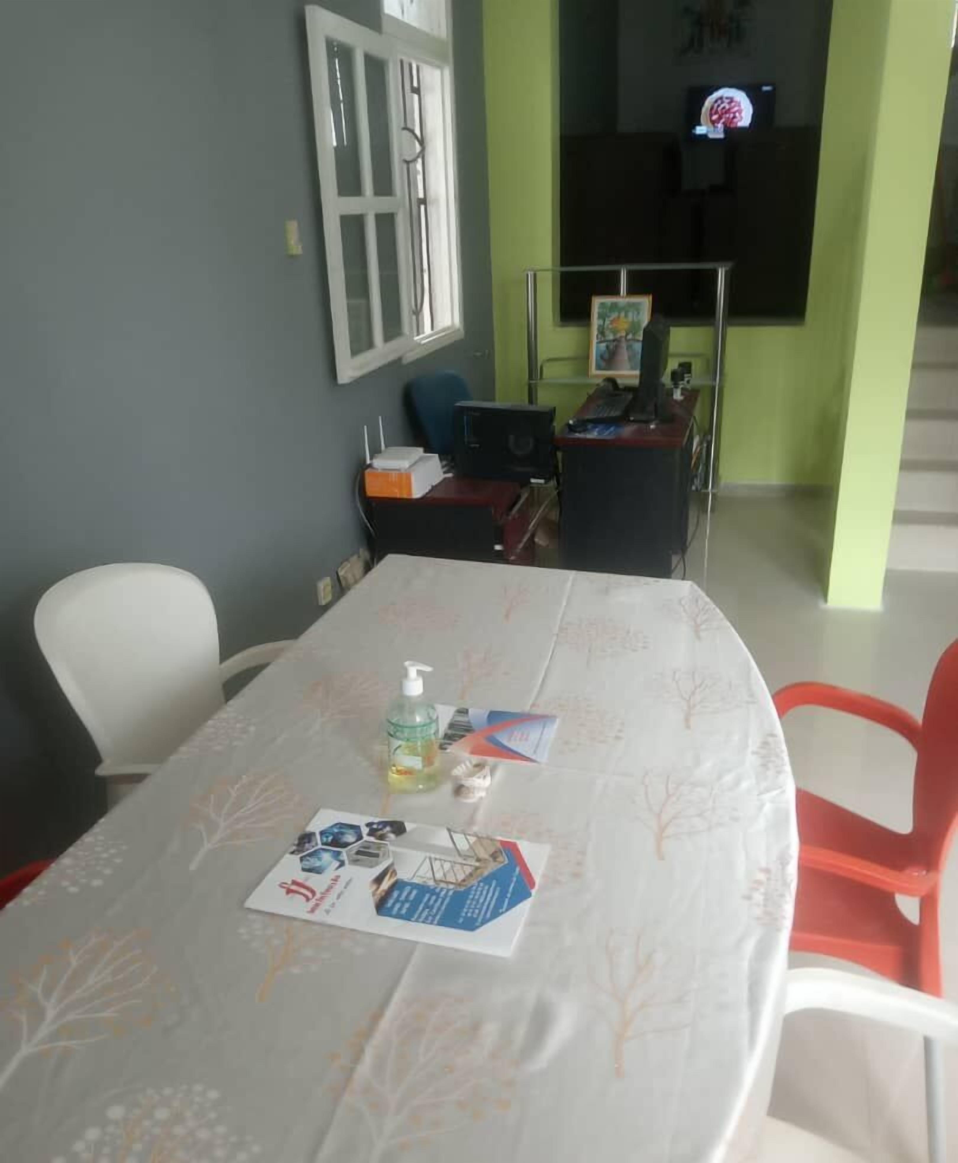 A dining area with a table set for two, a window, and a television in the background.