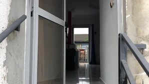 Un couloir avec une porte-fenêtre coulissante donnant sur une pièce. Le sol est recouvert de carreaux imitant le marbre.