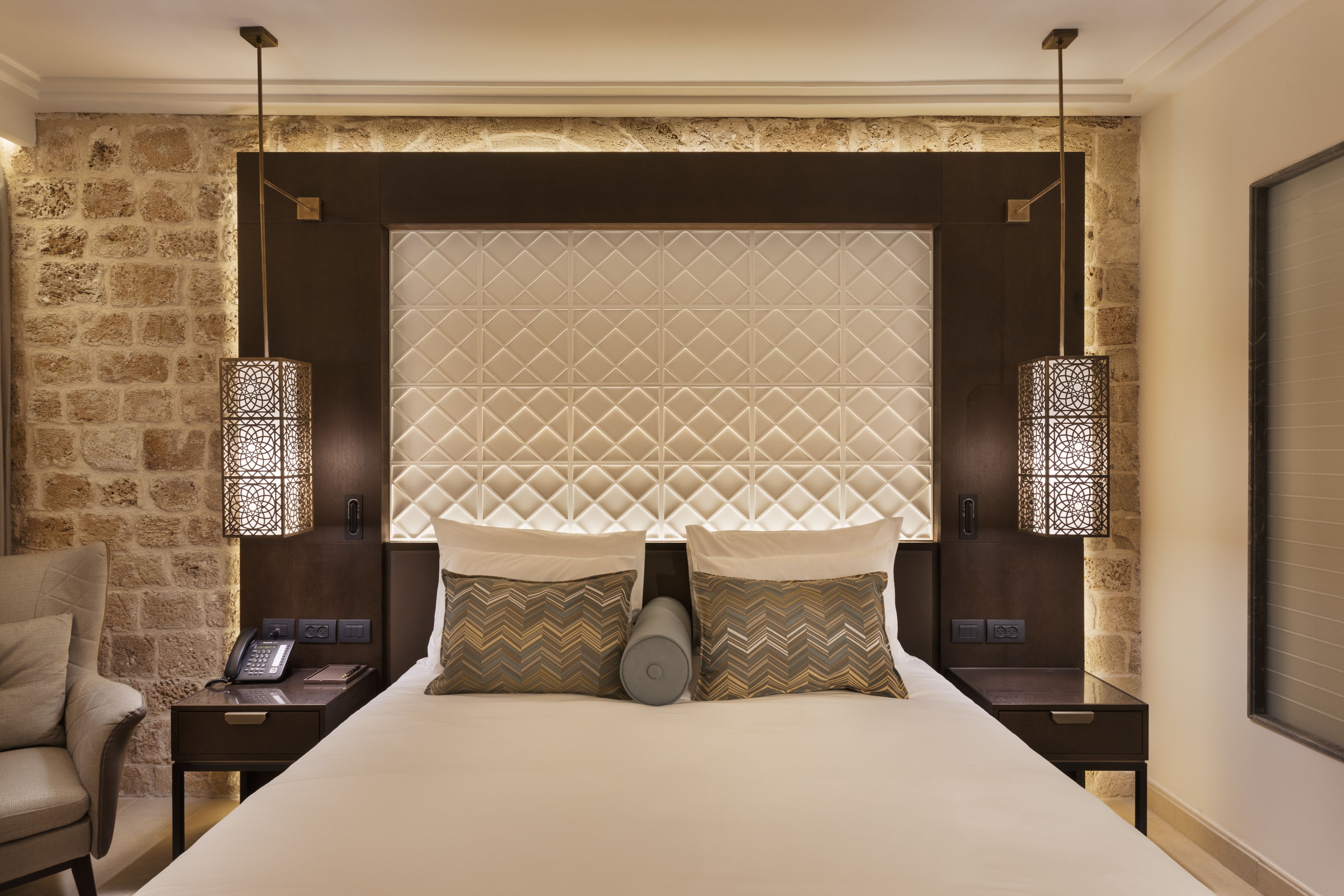 A hotel room with a large bed, two bedside tables, a telephone, and a chair.