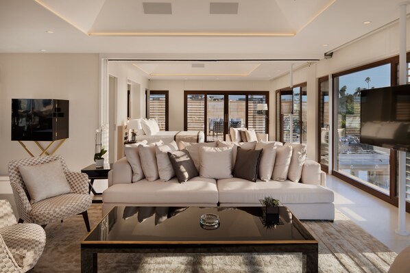 A modern living room with a large sofa, a coffee table, and a television. - The Setai Tel Aviv, a Member of the leading hotels of the world (Tel Aviv)
