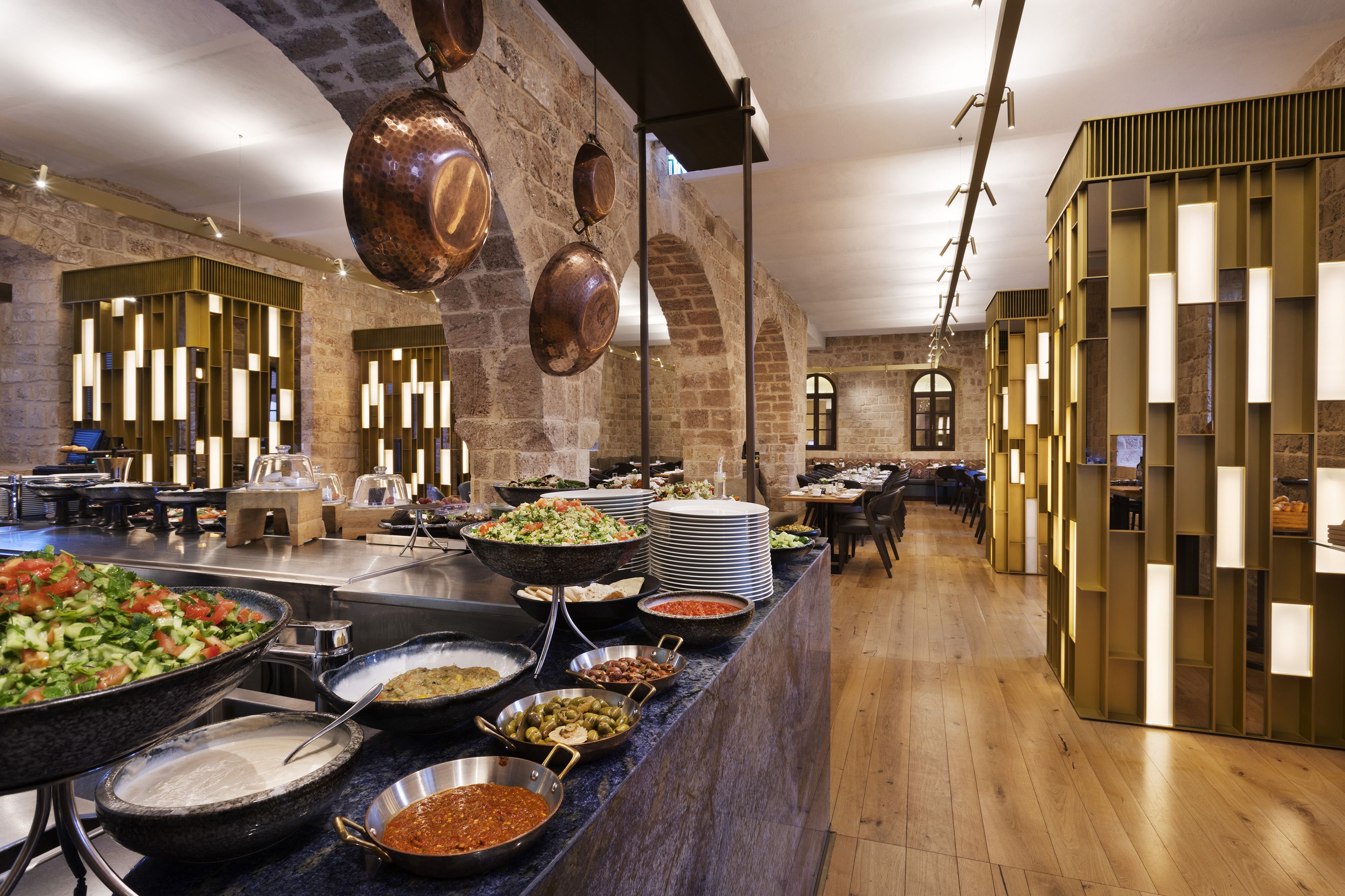 Angolo buffet con diverse opzioni di cibo, parete in mattoni e pentole di rame appese.