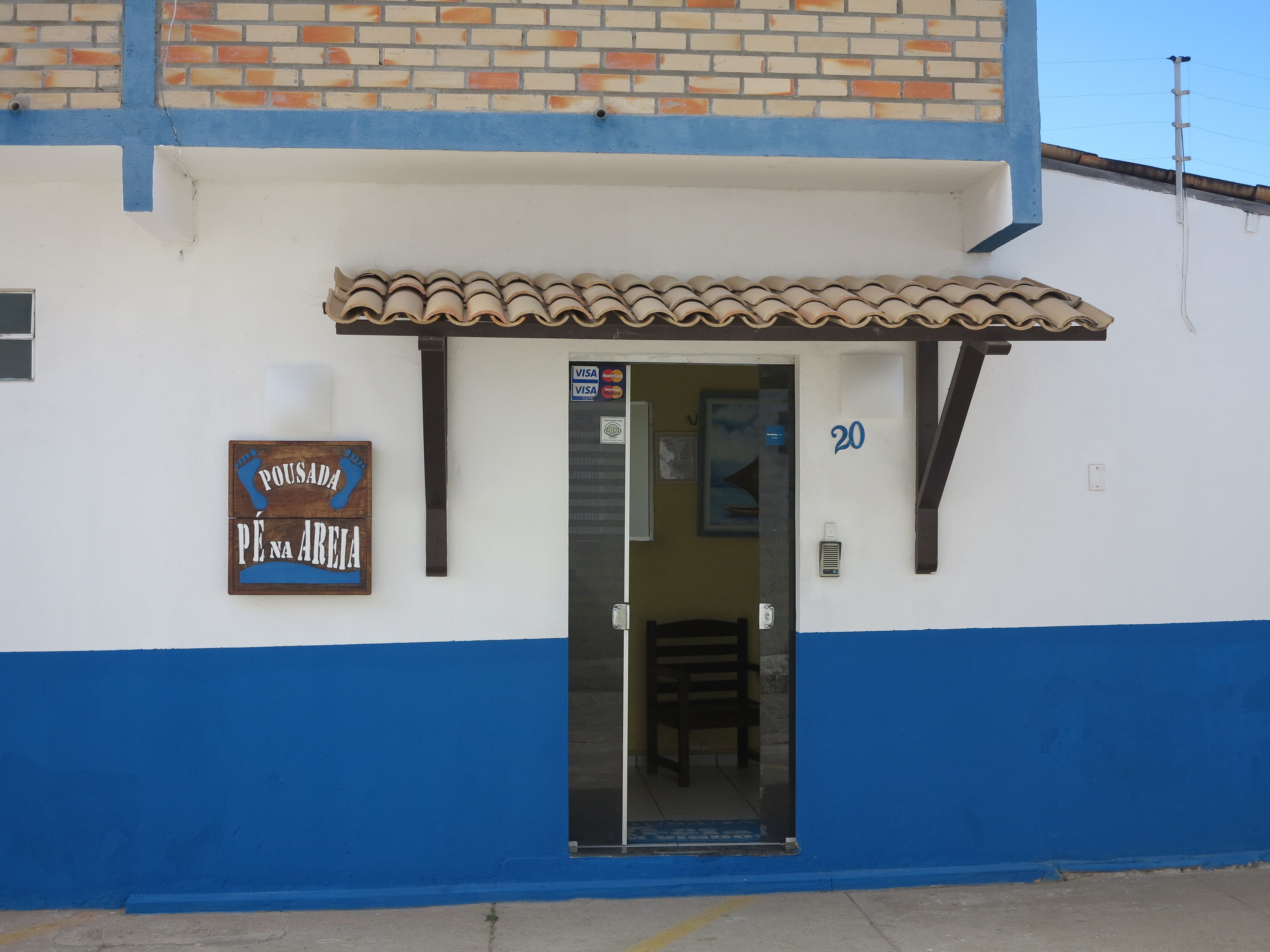 Ein Gebäude mit einer blau-weißen Fassade, einem Zeltvorzelt und einer Tür mit einem 'VISA'-Schild.