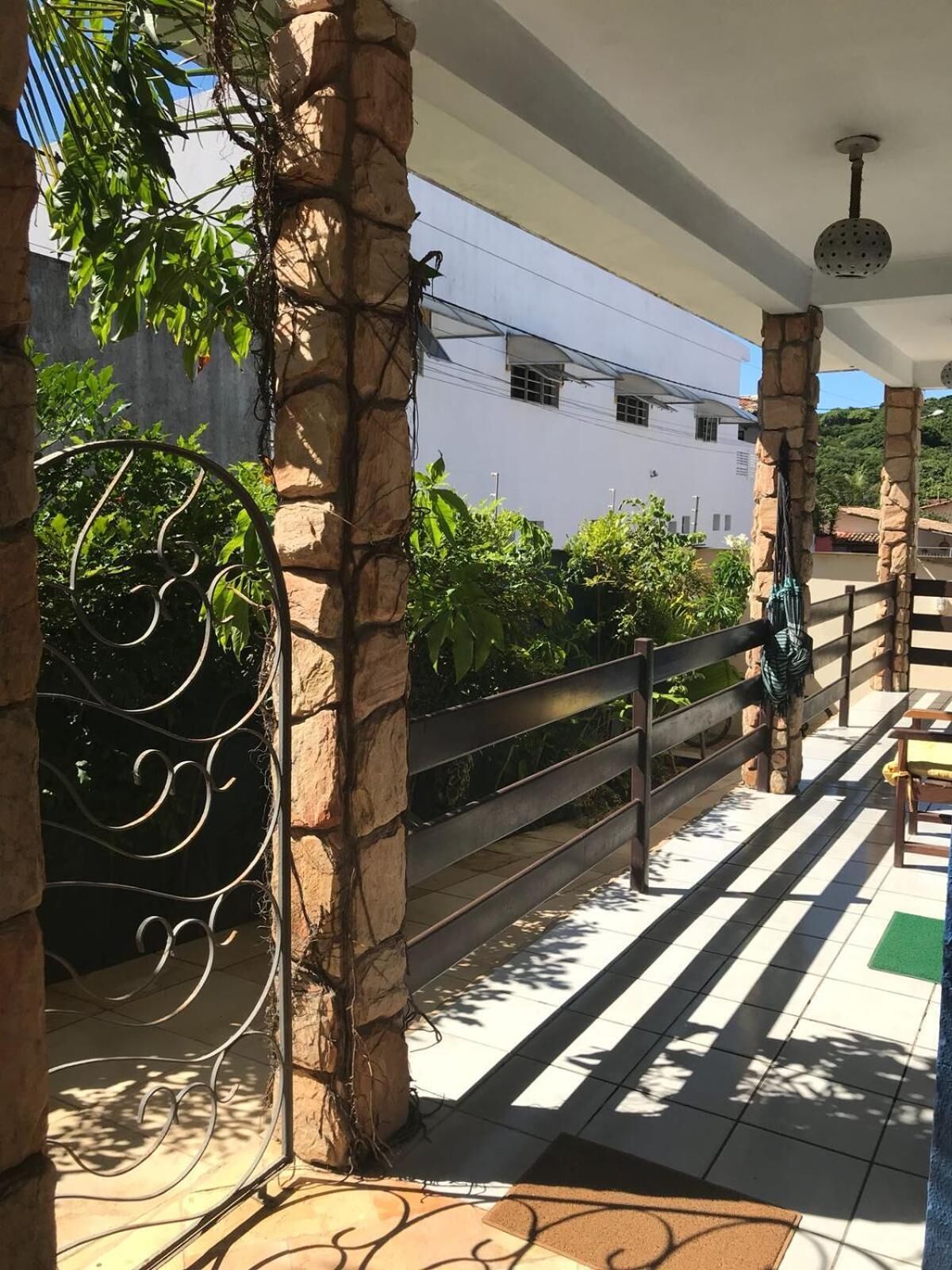 A covered outdoor area with stone pillars, a metal gate, and a tiled floor.