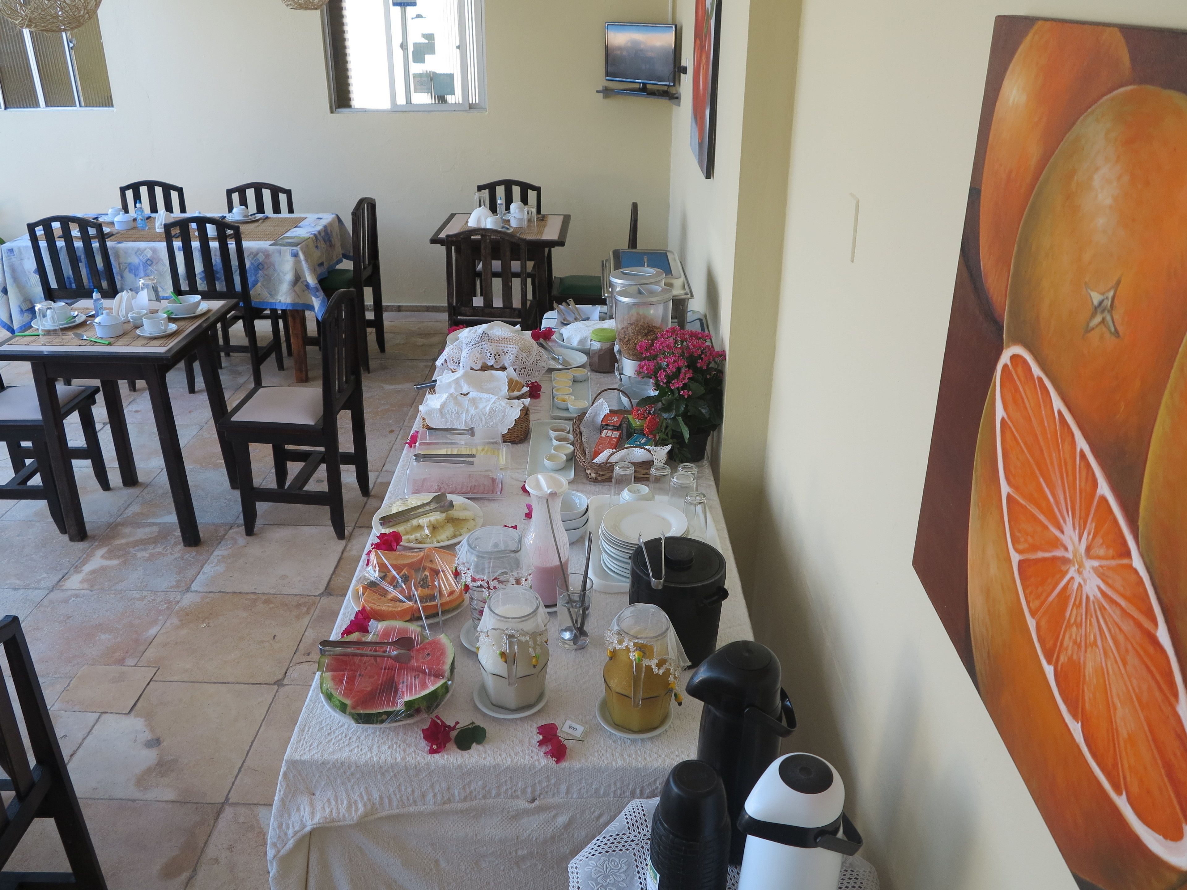A dining area with tables set for breakfast, including plates, bowls, and a variety of food items.