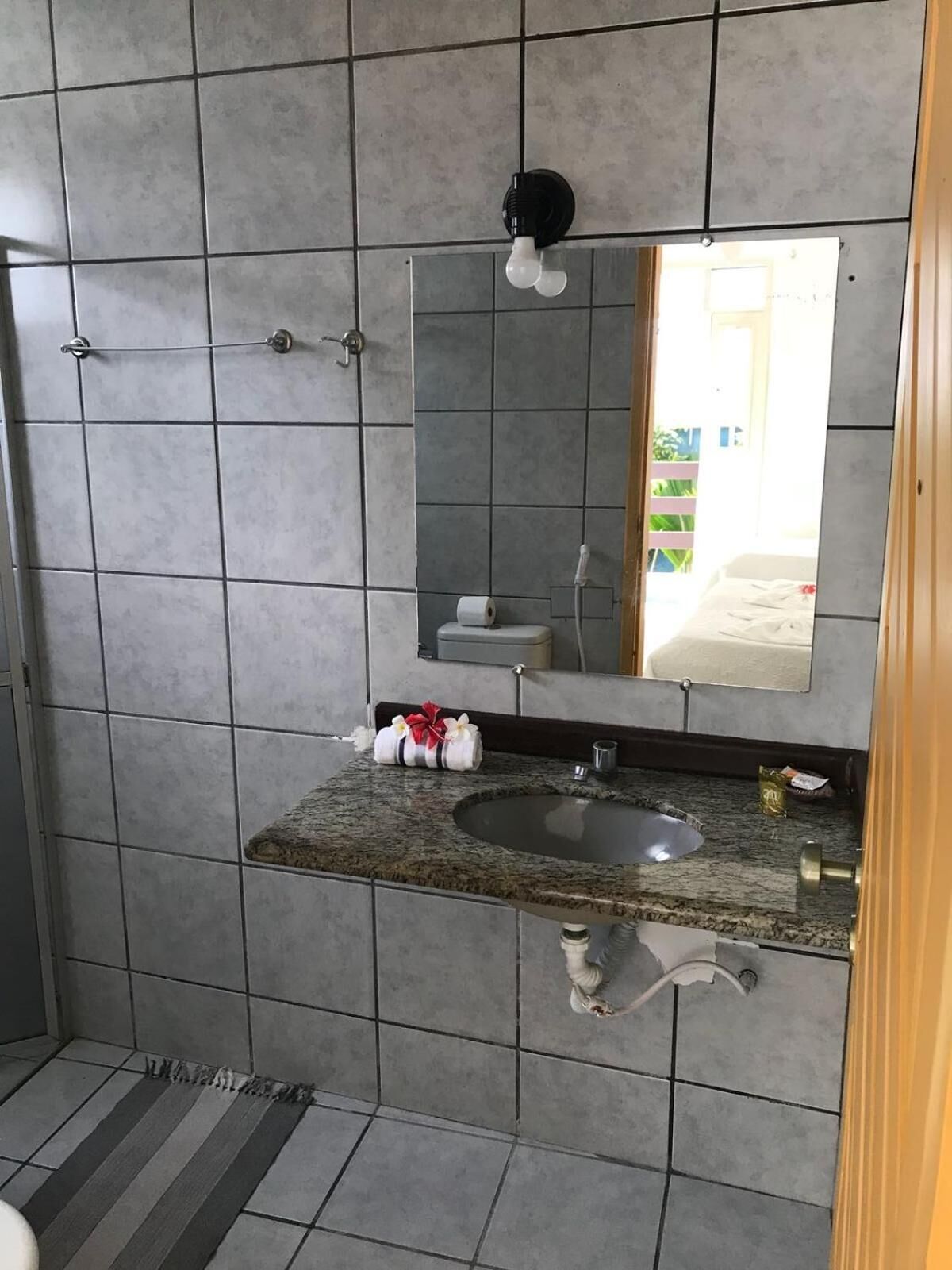 A bathroom with a granite countertop sink, a towel rack, a toilet, and a mirror.