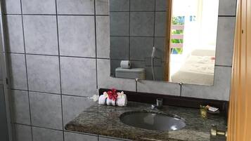 Een badkamer met een wastafel met een granieten blad, een handdoekrek, toilet en spiegel.