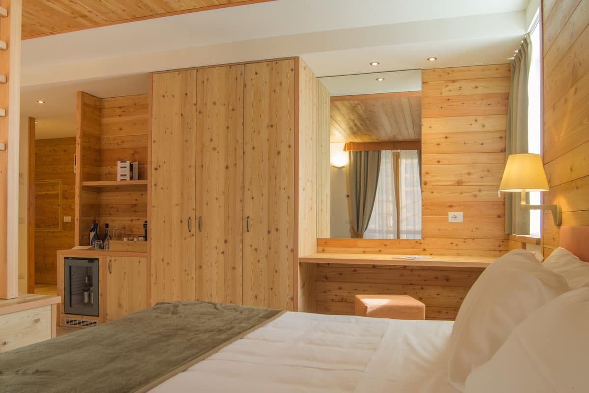 Une pièce aux murs lambrissés, avec un lit, une petite table et un miroir.