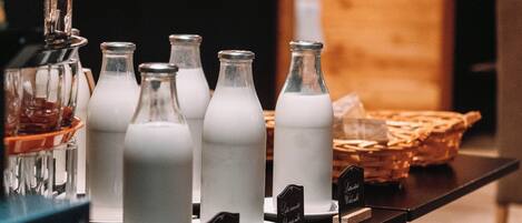 A selection of milk bottles on a counter with labels, a blender, and a basket in the background.