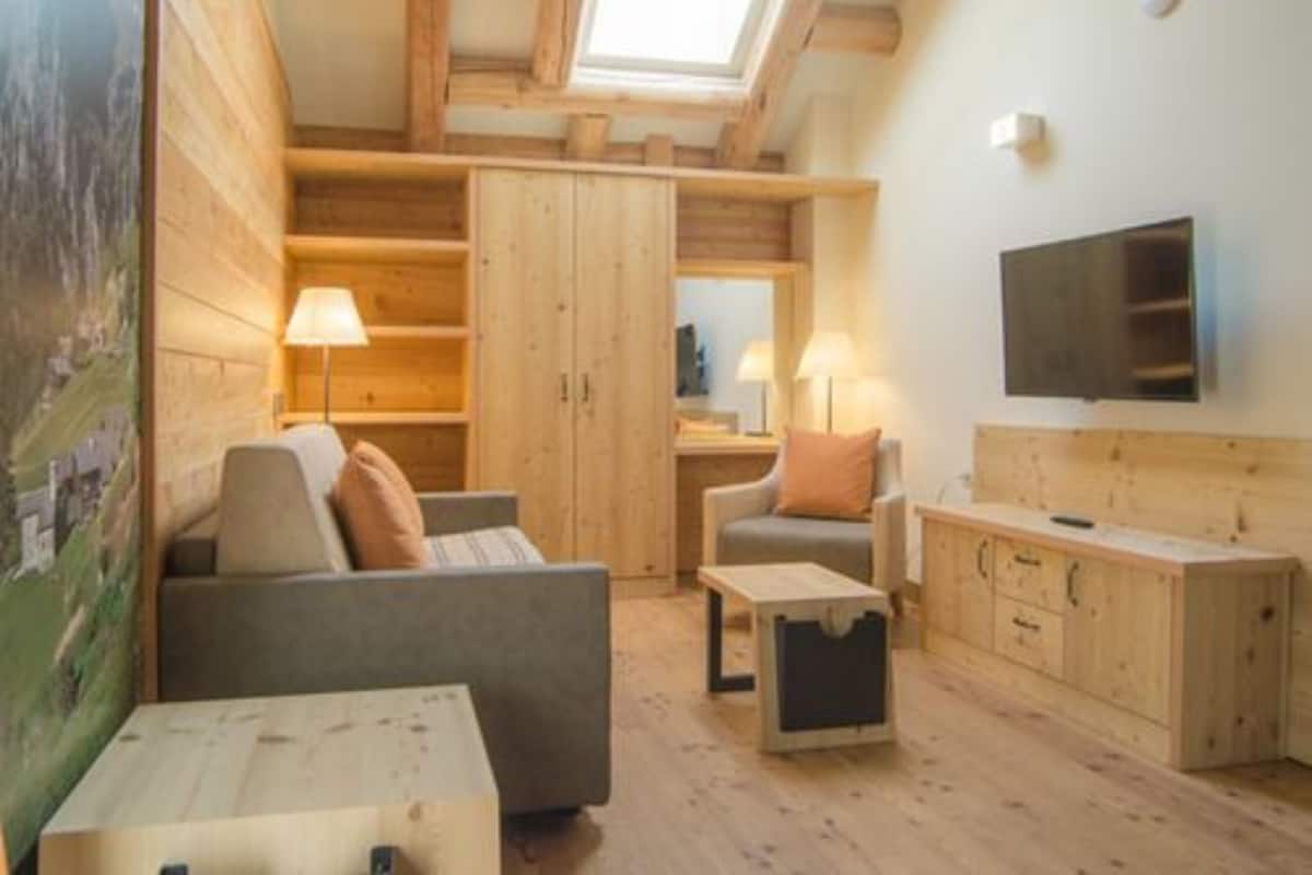 Une pièce chaleureuse avec un lit en mezzanine, des meubles en bois et un téléviseur fixé au mur.
