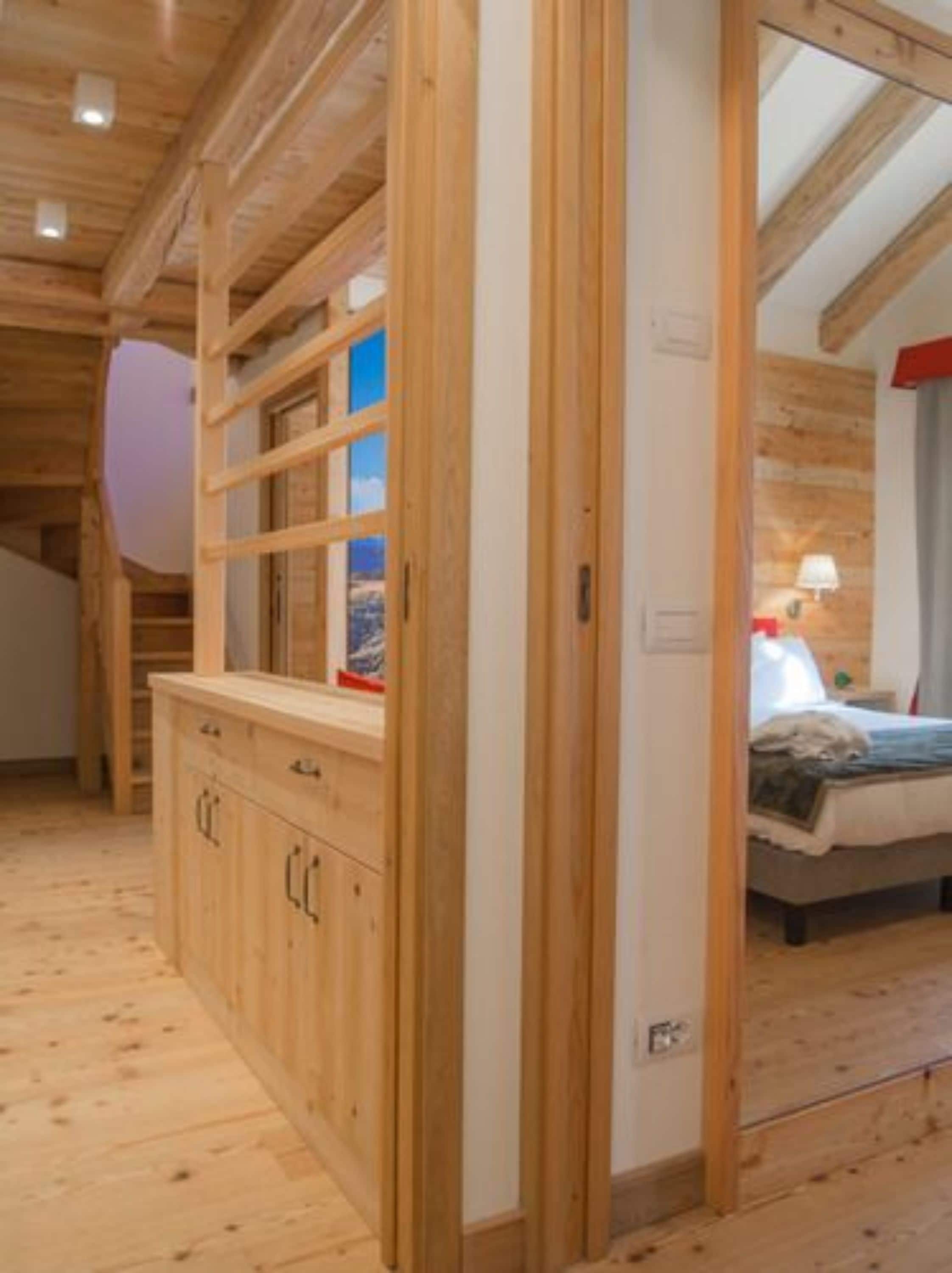 A wooden interior with a bed, a nightstand, and a wooden cabinet.
