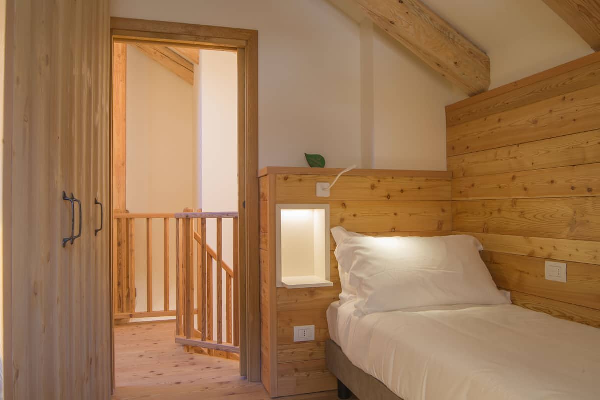 Une pièce en bois avec un lit, une fenêtre et une porte donnant sur une autre pièce.