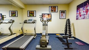 Un gimnasio con cintas de correr, elíptica y banco de pesas.