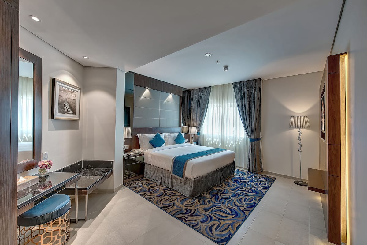 A modern hotel room with a large bed, a desk, and a chair.